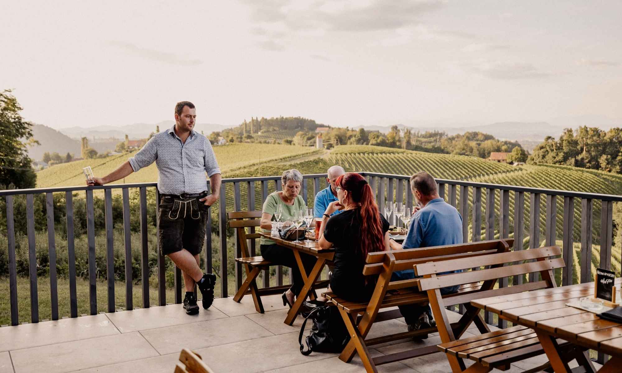 Gäste genießen regionale Spezialitäten und Wein auf der Panoramaterrasse des Weinguts Pilch mit herrlichem Panoramablick über die Weinberge der Südsteiermark.